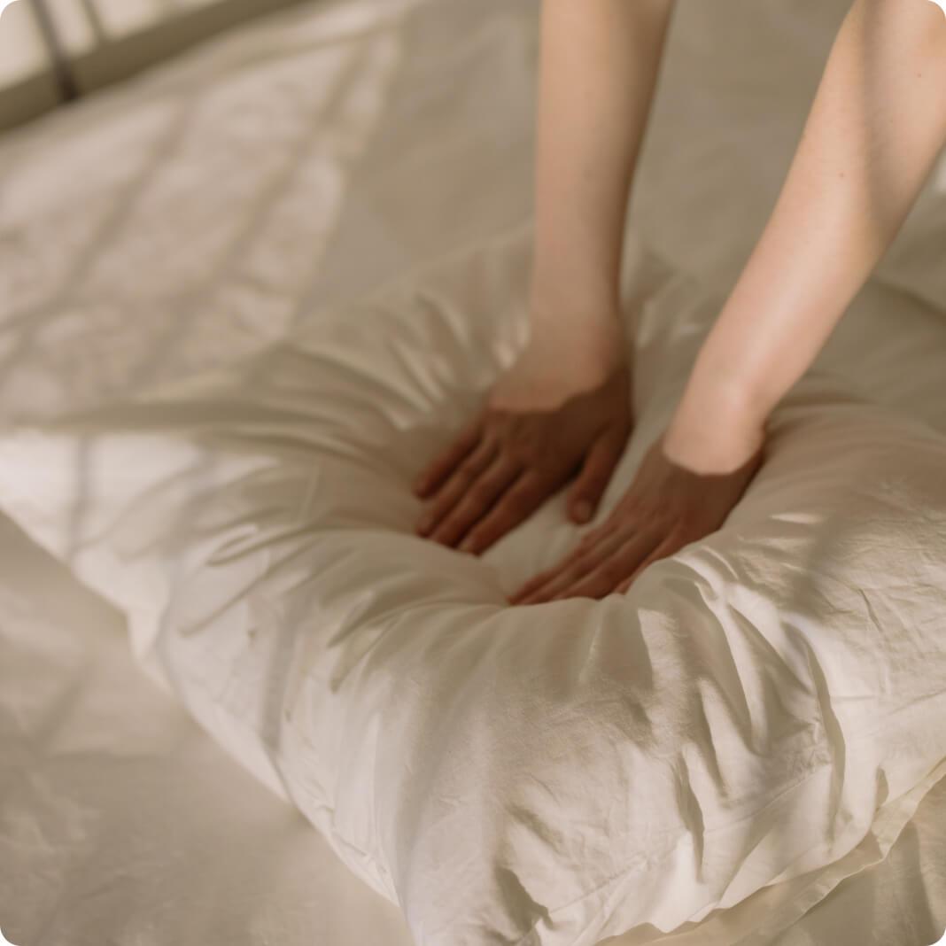 Close-up image of hands smoothing bedsheets